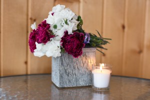 A bouquet of flowers sits on top of a slate box, which holds the ashes of a baby boy named Amos. A lit white votive candle sits in front of the box.